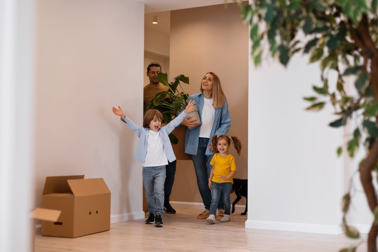 Eine Familie zieht in ihr neues Zuhause ein, ein Kind jubelt mit ausgebreiteten Armen