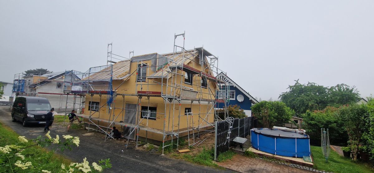 Einfamilienhaus im Rohbau mit gelber Fassade und Baugerüst in Königswinter