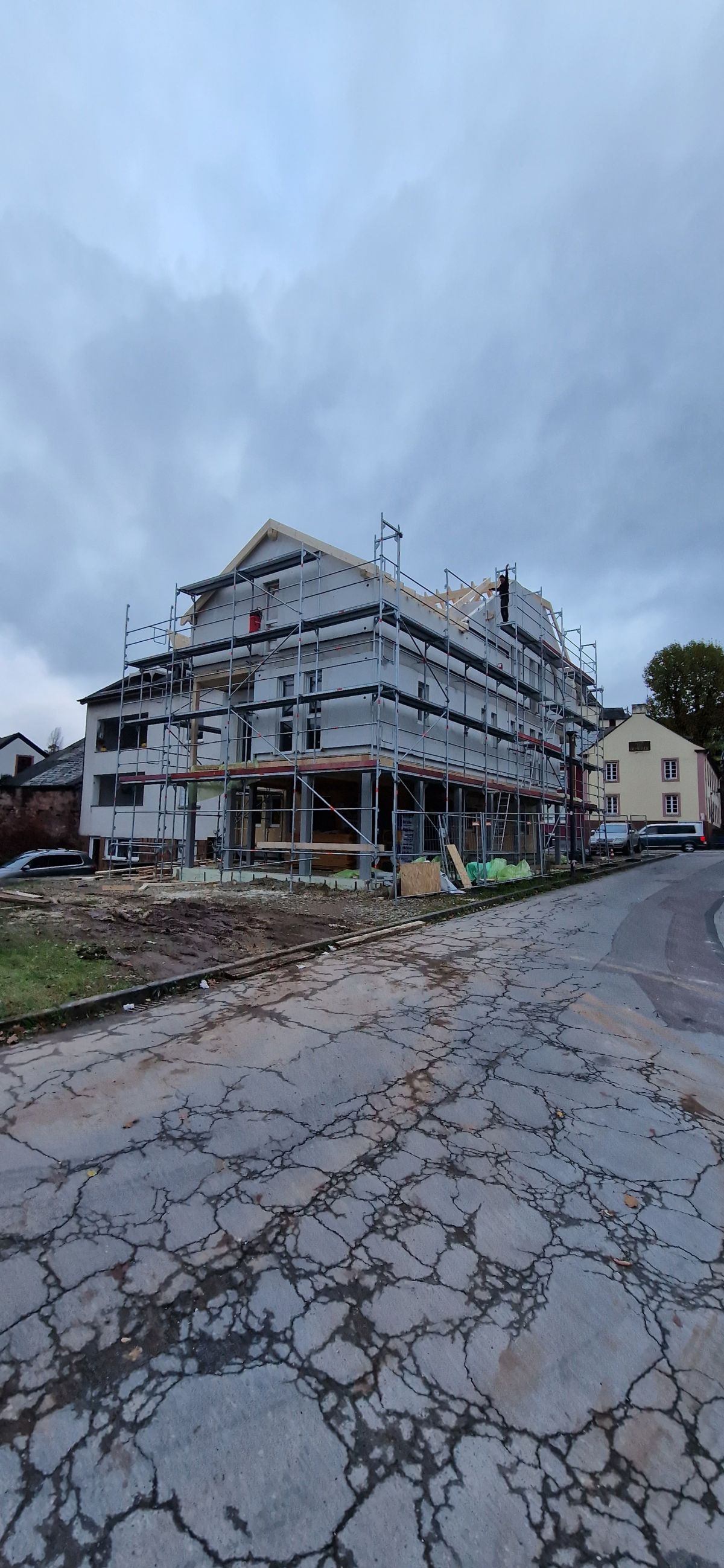 Eingerüstetes Mehrfamilienhaus im Rohbau an einer Straße in Trier